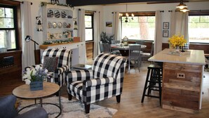 A cozy living room with checkered armchairs, a wooden coffee table, and a dining area with a table and chairs. - Great Getaway on the Big Thompson very near Estes & Rocky Mt. Nat'l Park (Drake)