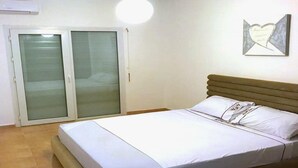 Un dormitorio con cama, puerta corrediza de vidrio y una obra de arte colgada en la pared.