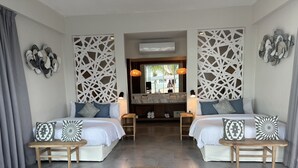 Een hotelkamer met twee bedden, een geweven vloerkleed, decoratieve wandpanelen en uitzicht op het zwembad.