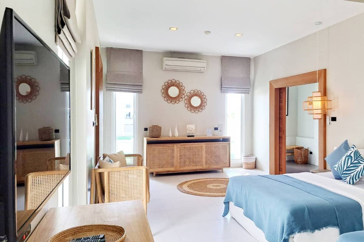 Un dormitorio moderno con cama, mesitas de noche, cómoda y espejo.