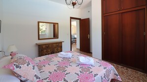 Ein Schlafzimmer mit Bett, Kommode, Spiegel, Chandelier und Kleiderschrank.