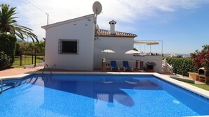 Ein Schwimmbad mit einem weißen Gebäude im Hintergrund, einer Satellitenschüssel und blauem Himmel.