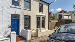 A two-story house with a blue front door, a garage, and a driveway. - Stylish Apartment In Leafy Central Neighbourhood (Cardiff)