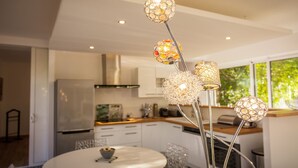 A modern kitchen with white cabinets, a stainless steel refrigerator, and a dining area with a round table and chairs. - Villa with private pool and spa (CARNAS)