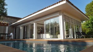 A modern house with a swimming pool, large glass doors, and a patio area. - Villa with private pool and spa (CARNAS)
