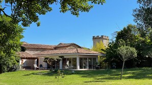 A villa with a tiled roof, a stone tower, and a well-maintained garden. - Villa with private pool and spa (CARNAS)