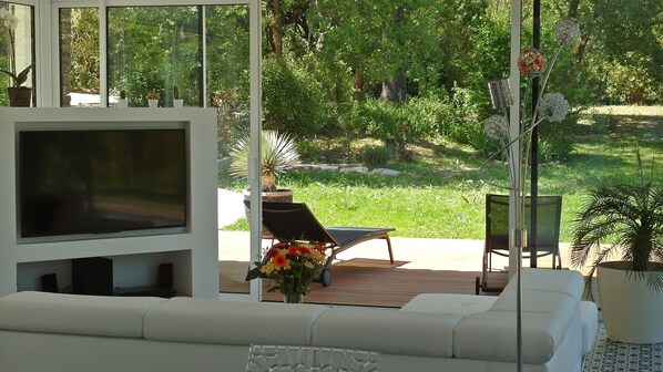 A modern outdoor living area with a flat-screen TV, a sofa, and a dining table.