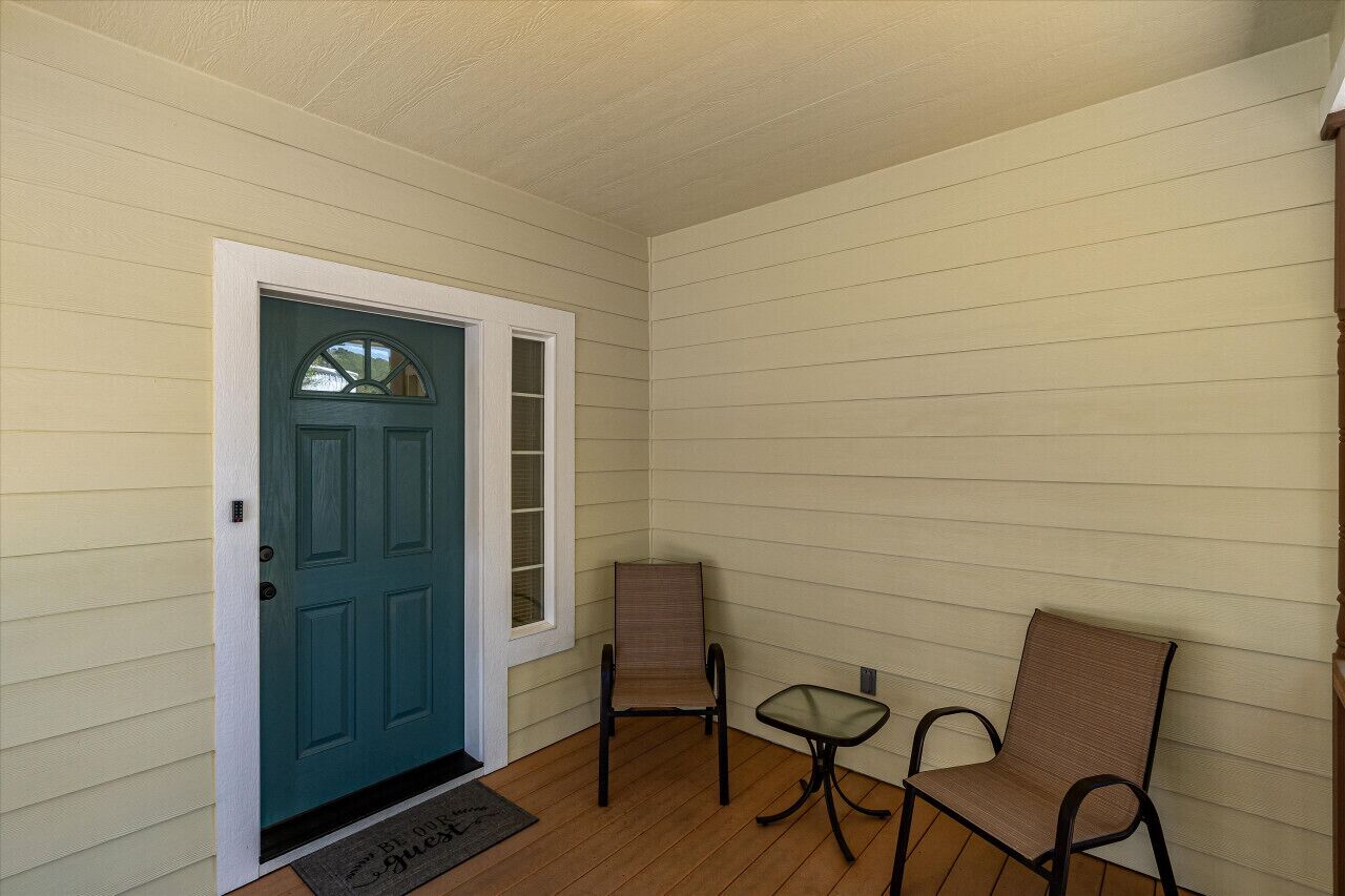 A room with a teal door, two chairs, and a small table.