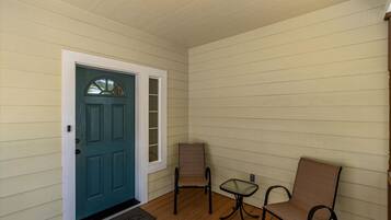 A room with a teal door, two chairs, and a small table.