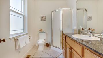 A bathroom with a toilet, shower, and sink.