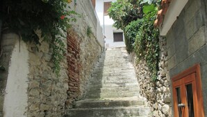 A narrow stone staircase leading up to a building with a wooden door and window.