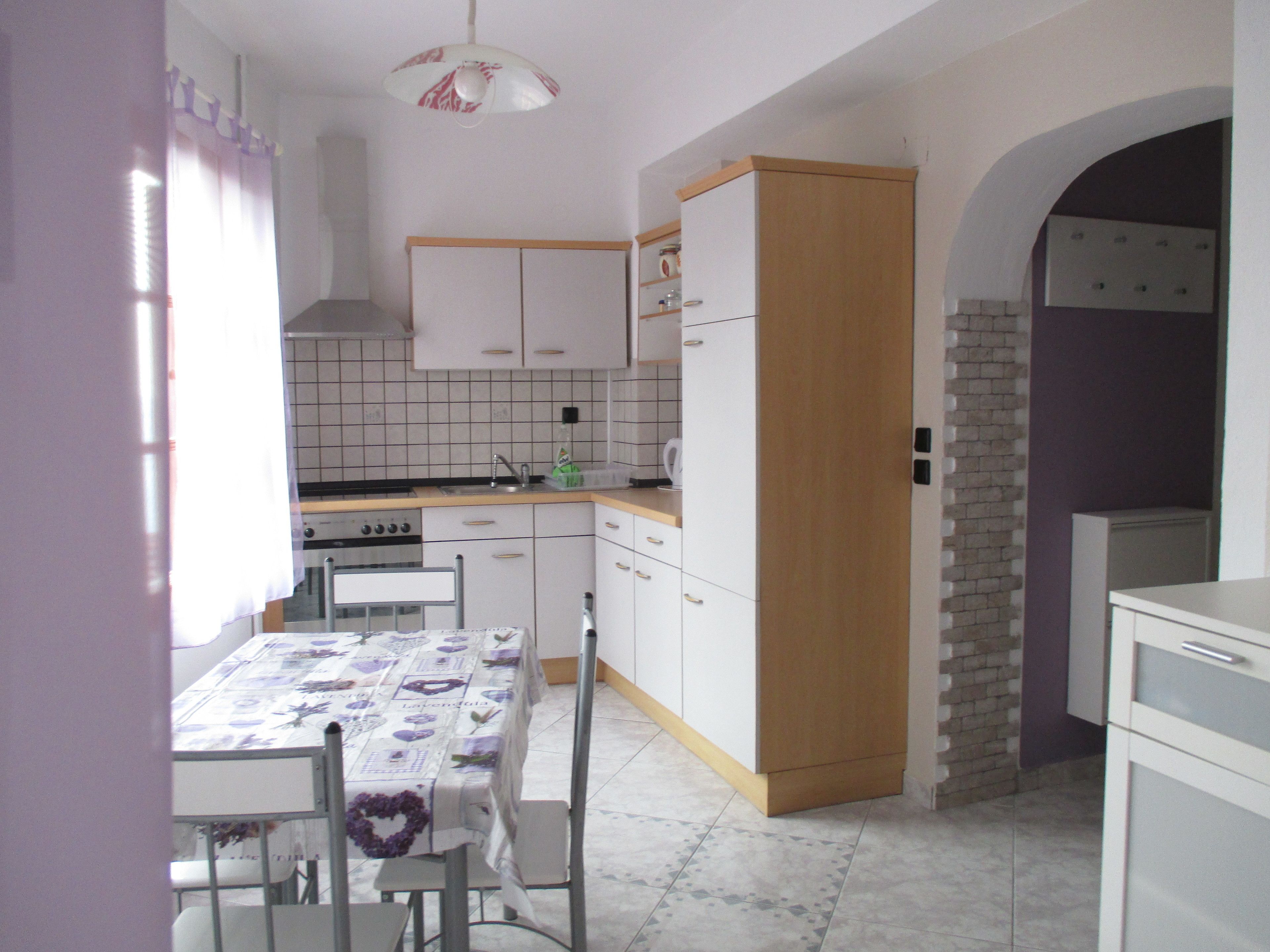 A compact kitchen with white cabinets, a wooden door, and a tiled backsplash.