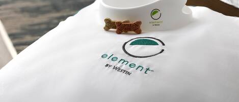 Un almohadón blanco con el logo “element by Westin” y un pequeño objeto con forma de hueso encima.