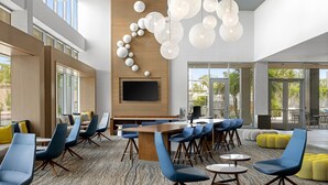 Ein moderner Lounge-Bereich mit einem langen Tisch, blauen Stühlen und einem großen Bildschirm.