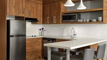 Una cocina moderna con armarios de madera, un refrigerador de acero inoxidable, un microondas y una encimera blanca.