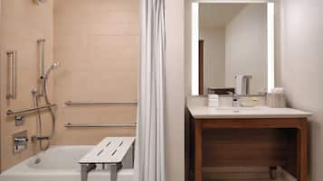 Une salle de bain équipée d’une baignoire, d’une douche et d’un meuble-lavabo en bois avec un miroir.