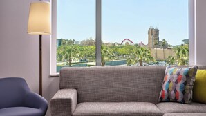 Ein Zimmer mit einer Couch, einer Lampe und einem Fenster mit Blick auf einen Park und Gebäude.