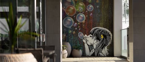 A modern building exterior with a mural of a woman blowing bubbles.