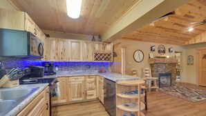 A kitchen with wooden cabinets, a built-in stove, and a stone fireplace. - Pet Friendly  w/ Private Dock - Steps to Rice Lake (Rice Lake)
