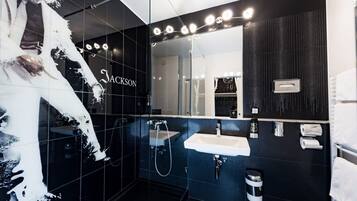 A modern bathroom with a black and white color scheme, a large mirror, and a sink with a handheld showerhead.