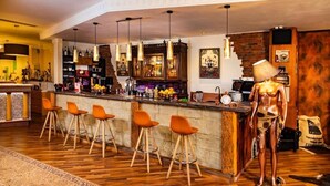Un espace bar doté d’un comptoir en bois, de plusieurs suspensions et de tabourets de bar orange.