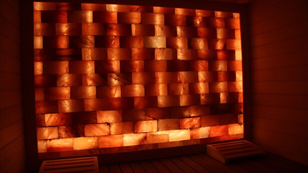 Un sauna avec un banc en bois et un mur de pierres chauffées.