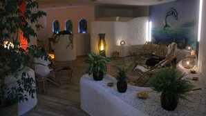 Un espace spa doté d’un comptoir d’accueil blanc, d’un coin salon avec des fauteuils et d’une fresque représentant un dauphin sur le mur.