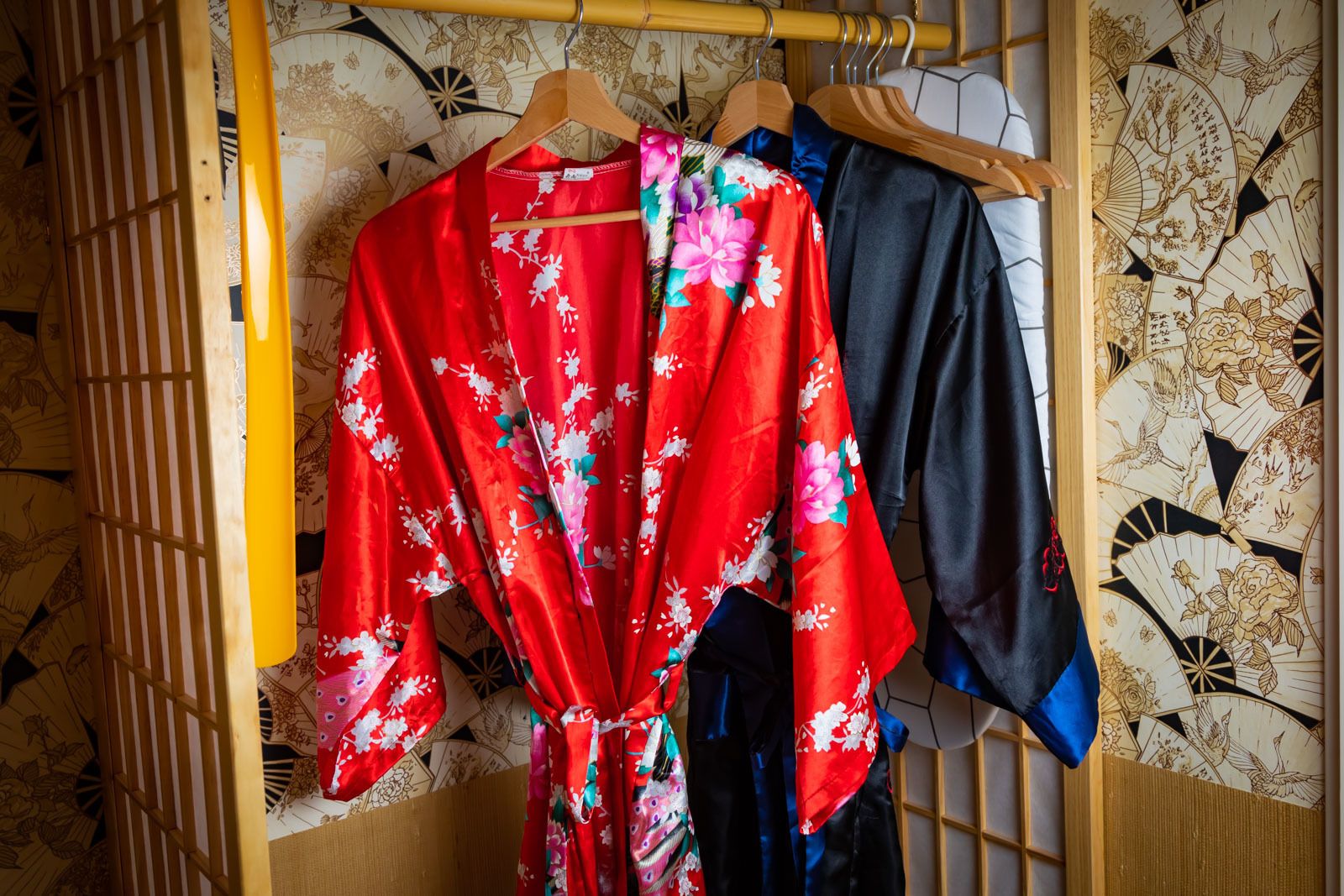 A traditional Japanese wardrobe with a wooden lattice door and a fan with floral designs on the wall.