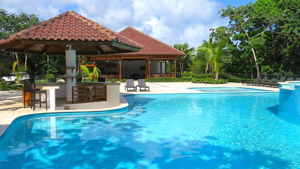 Una piscina con zona cubierta y sillas de descanso.