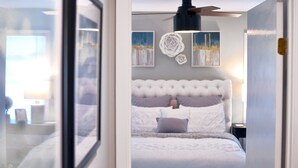 A bedroom with a tufted headboard, a ceiling fan, and artwork on the walls. - "NEW" Designed for Comfort and Relaxation and close to everything! (Hot Springs)