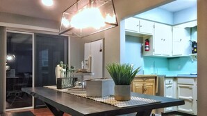 A modern kitchen with white cabinets, a wooden dining table, and a potted plant. - "NEW" Designed for Comfort and Relaxation and close to everything! (Hot Springs)