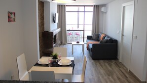 Un salon moderne comprenant un coin repas, un canapé et un téléviseur fixé au mur.