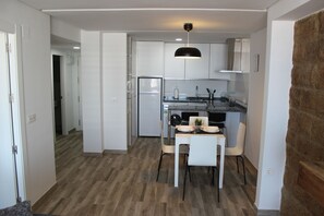 A compact kitchen with white cabinets, a built-in refrigerator, and a dining area with a table and chairs.