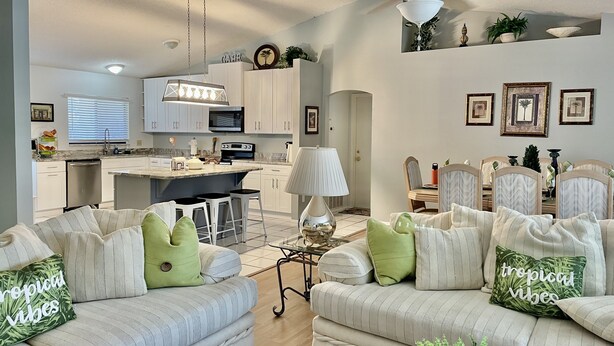 A modern living room with a sofa set, a dining area, and a kitchen. - Pool home near Disney parks. (Kissimmee)