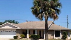 A single-story house with a garage, a front lawn, and a palm tree. - Pool home near Disney parks. (Kissimmee)