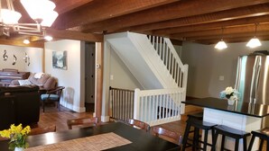 A dining area with a wooden table and chairs, a piano, and a staircase leading to another level. - Spacious! Recent Remodel! 6 Min. to Raystown Lake! Linens&Towels provided! (Saxton)