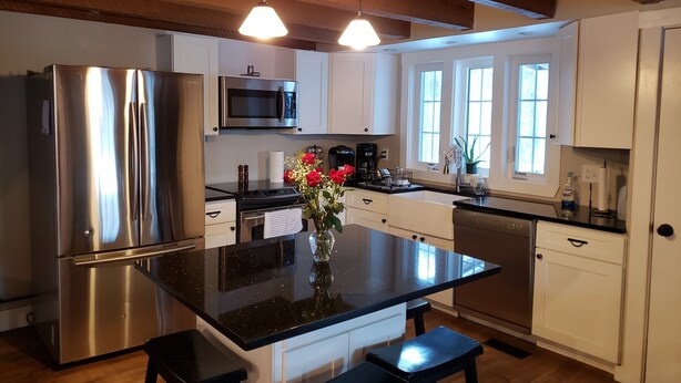 A modern kitchen with stainless steel appliances, a black granite island, and white cabinetry. - Spacious! Recent Remodel! 6 Min. to Raystown Lake! Linens&Towels provided! (Saxton)