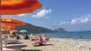 Ein Strand mit Sonnenschirmen, Liegestühlen und entspannten Menschen.