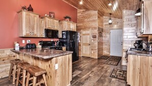 Eine Küche mit Holzausstattung, einer zentralen Kochinsel mit Sitzgelegenheiten, einem Kühlschrank und einer Mikrowelle.