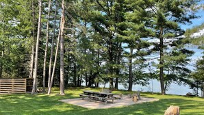 Ein Picknickplatz mit Bänken und Tisch, umgeben von hohen Bäumen und einem Holenzaun.
