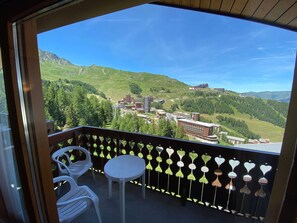 A balcony with a view of a mountainous landscape, a table, and two chairs. - Appartement proche des pistes | Balcon ou Terrasse (Aime)
