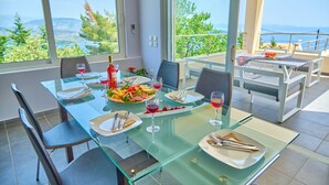 Un espace repas avec une table en verre, des chaises et une vue panoramique grâce à de grandes fenêtres.