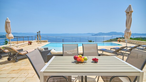 Un espace aménagé au bord de la piscine, avec des chaises longues et une table où sont disposés des fruits.