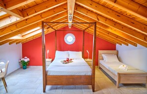 Une chambre à coucher avec un lit à baldaquin, un lit simple plus petit, une lucarne et un mur d’accent de couleur rouge.