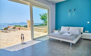 Une chambre dotée d’une grande porte-fenêtre coulissante donnant sur un balcon avec vue sur la mer.