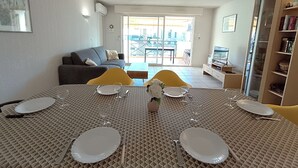 Un'area pranzo con tavolo imbandito per quattro persone, un divano e una TV sullo sfondo.