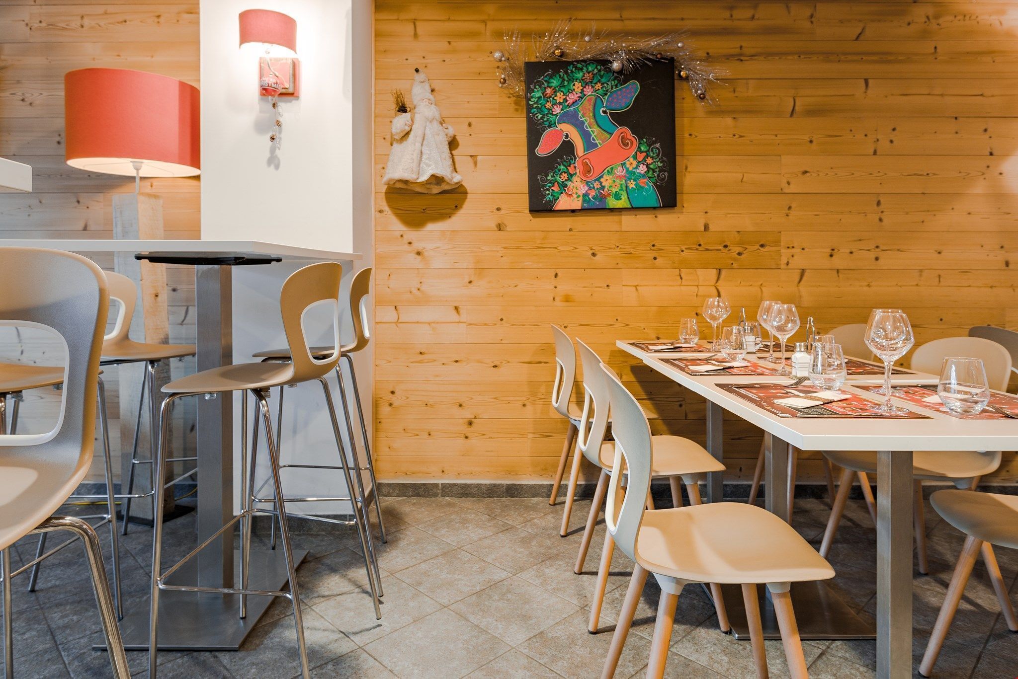 Un restaurant amb parets de fusta, cadires modernes i una taula de dinar preparada.