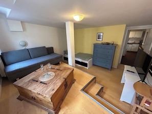 Ein gemütlicher Wohnraum mit Sofa, Couchtisch, Kommode und kleinem Bett.