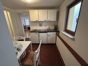 Eine kleine Küche mit weißen Schränken, einem Spülbecken und einem Fenster.