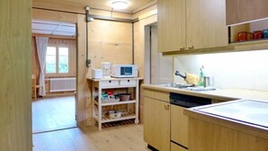 A compact kitchen with wooden cabinets, a microwave, and a small countertop. - Chalet Alte Post by Interhome (Schwenden)
